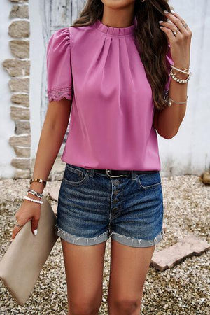 a woman wearing a pink blouse and denim shorts