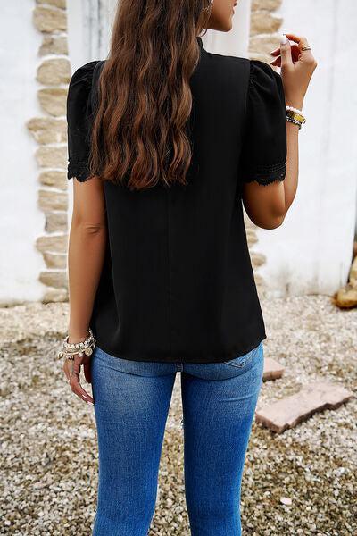 a woman in jeans and a black top is smoking a cigarette