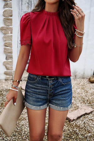 a woman wearing a red top and denim shorts