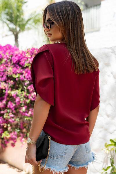 a woman wearing a red top and denim shorts