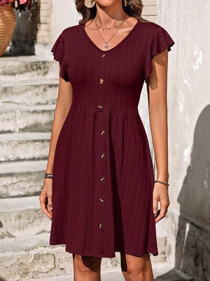 a woman wearing a maroon dress with buttons