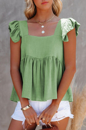 a woman wearing a green top and white shorts