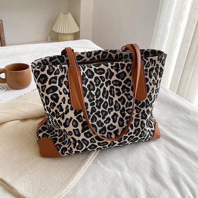a leopard print bag sitting on top of a bed