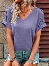 a woman wearing a purple top and ripped shorts