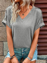 a woman wearing a grey top and ripped shorts