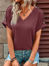 a woman wearing a burgundy top and ripped shorts