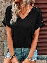 a woman wearing a black top and ripped shorts