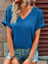 a woman wearing a blue top and ripped shorts
