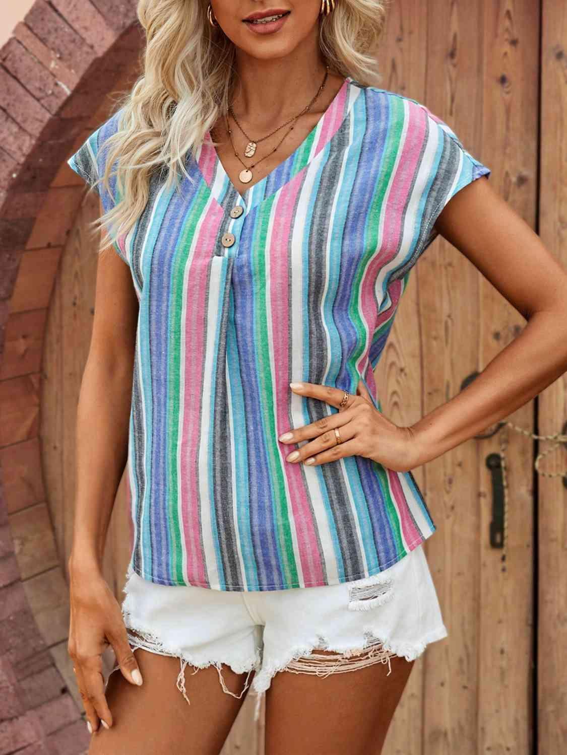 a woman wearing a colorful striped shirt and white shorts