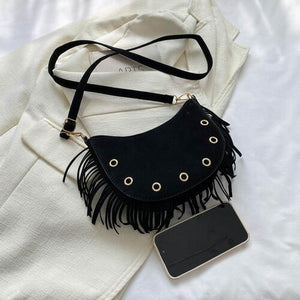 a black purse sitting on top of a white sheet