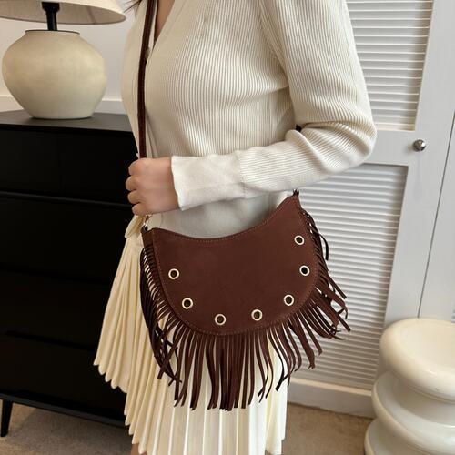 a woman wearing a white sweater and a brown purse