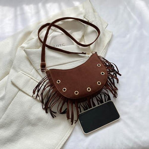 a brown purse sitting on top of a white blanket