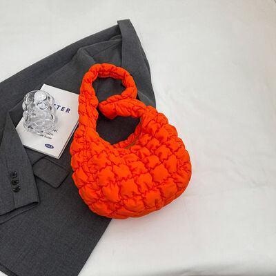 an orange purse sitting on top of a bed