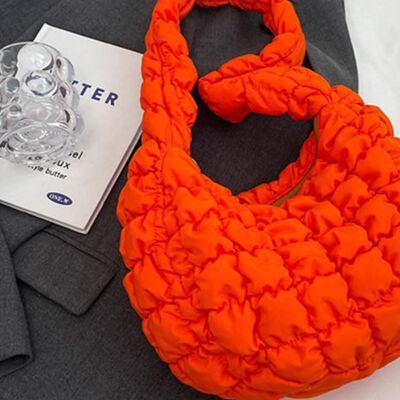 an orange purse sitting on top of a bed