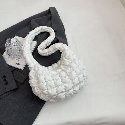 a white purse sitting on top of a bed