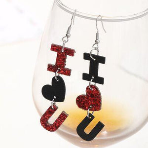 a pair of black and red earrings sitting on top of a wine glass