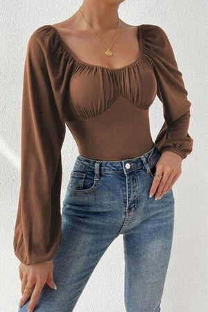 a woman wearing a brown top and jeans