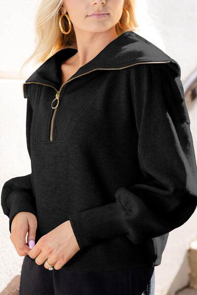 a woman wearing a black top with a gold zipper