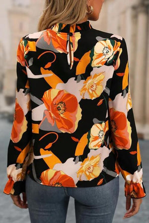 a woman wearing a black and orange floral blouse