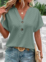 a woman wearing a green blouse and jeans