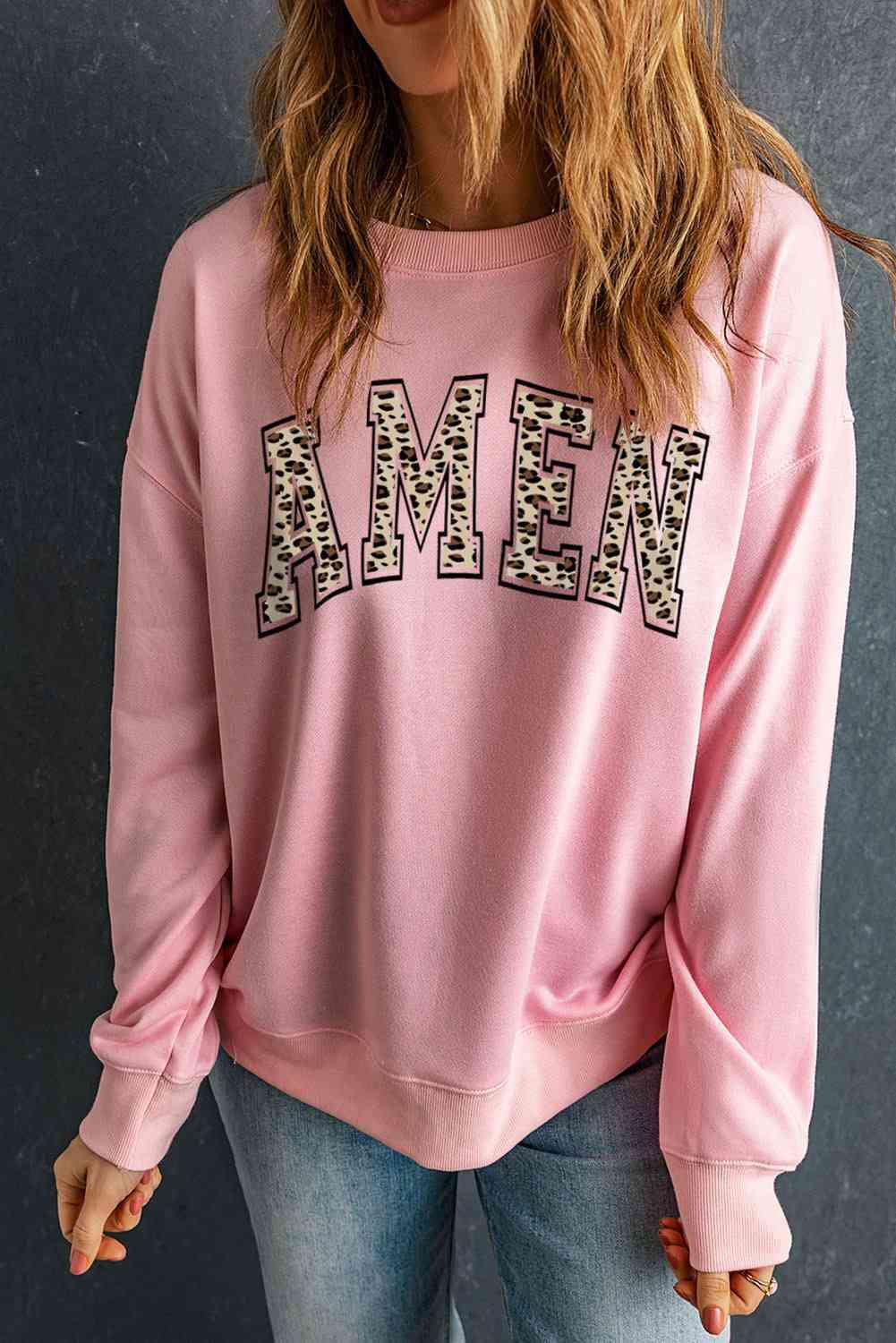 a woman wearing a pink sweatshirt with leopard print