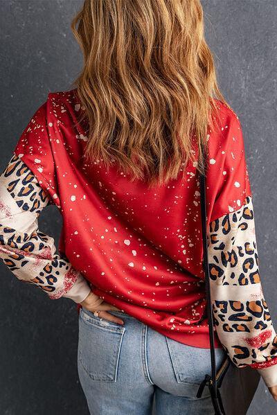 a woman wearing a red top with leopard print sleeves