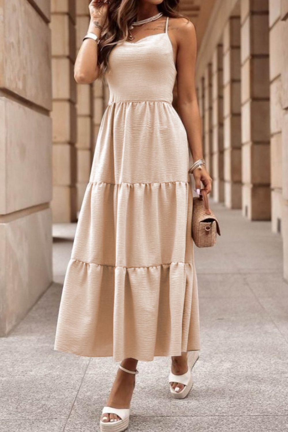 a woman in a beige dress standing on a sidewalk