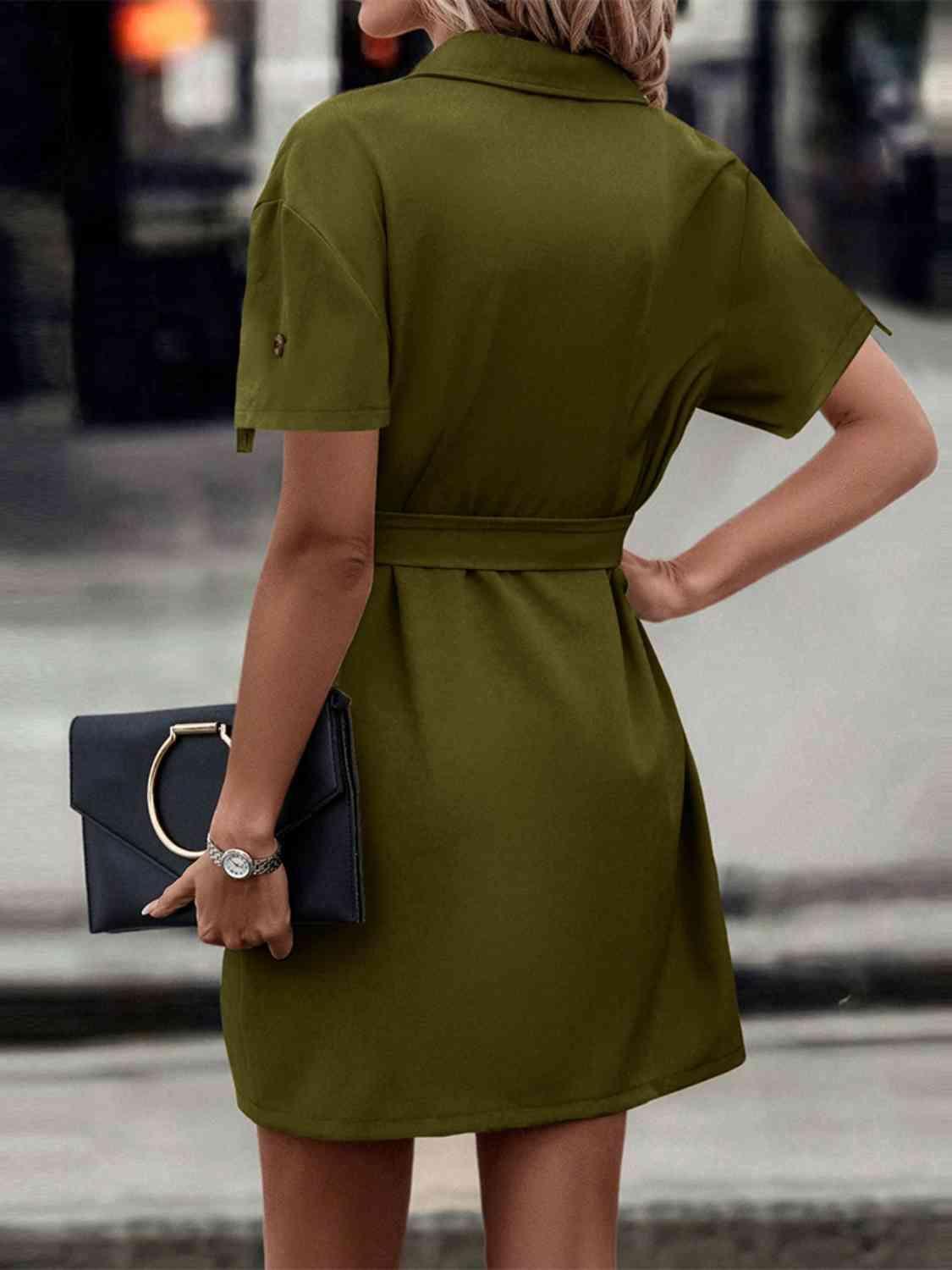 a woman in a green dress holding a black purse