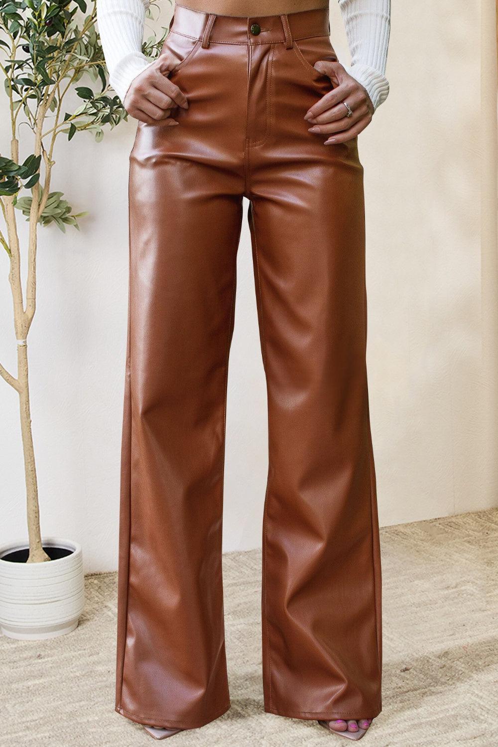 a woman wearing brown leather pants and a white shirt