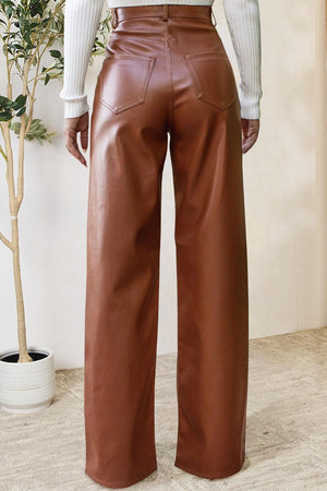 a woman wearing a white shirt and brown leather pants