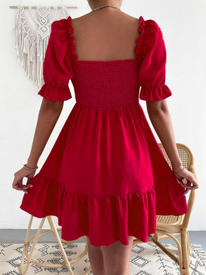 a woman in a red dress standing in front of a chair