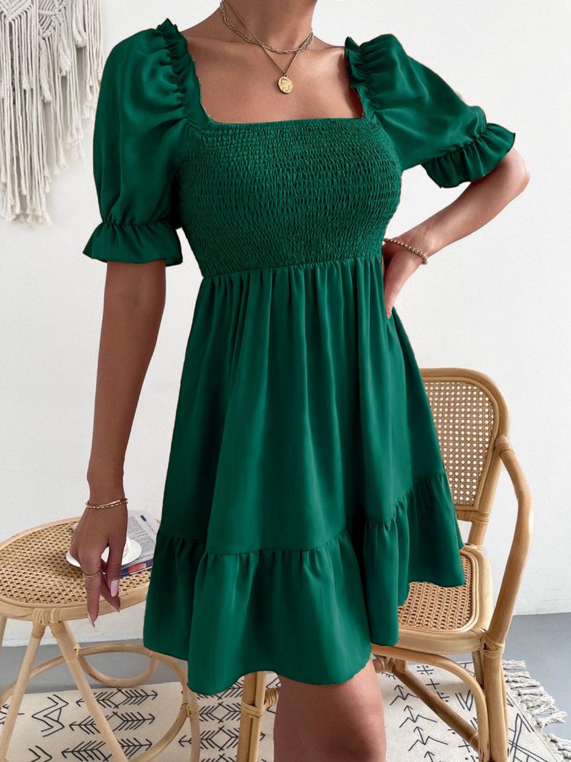 a woman in a green dress standing next to a chair