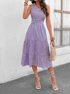 a woman wearing a purple striped dress and a straw hat