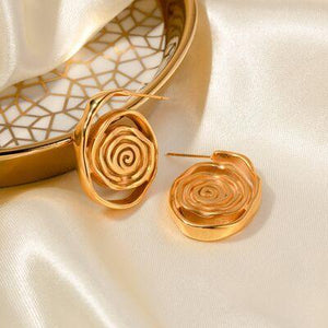 a pair of gold earrings sitting on top of a white cloth