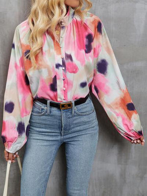 a woman with blonde hair wearing a colorful shirt and jeans