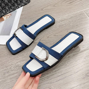 a hand is holding a pair of blue and white sandals