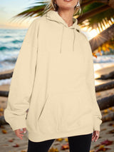 a woman standing on a beach wearing a hoodie