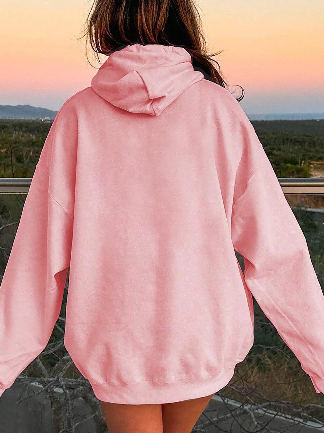 a woman in a pink hoodie looking at the sunset