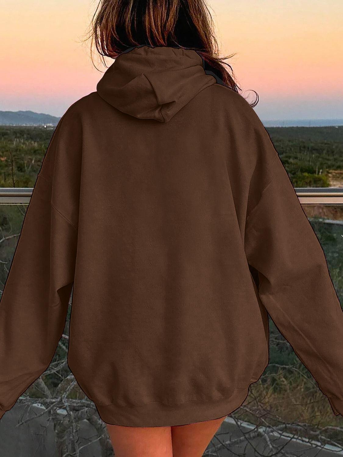 a woman in a brown hoodie looking out at the desert