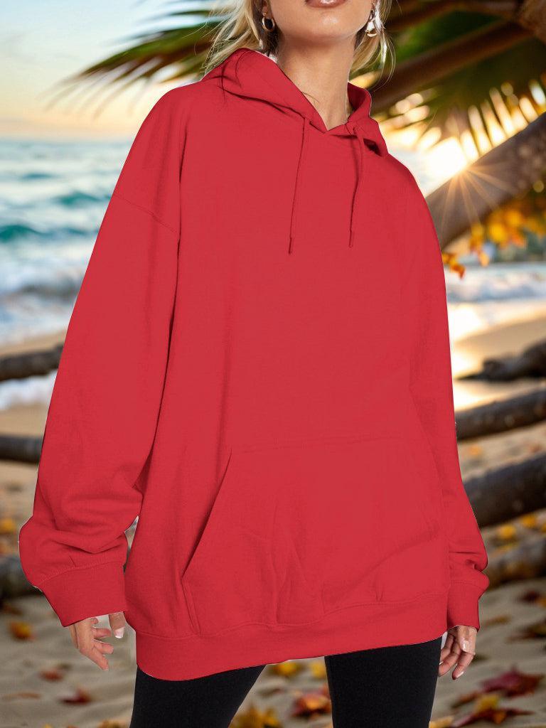 a woman standing on a beach wearing a red hoodie