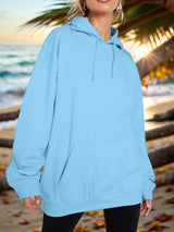 a woman standing on a beach wearing a blue hoodie