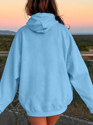 a woman in a blue hoodie looking at the sunset