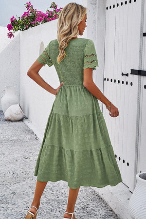 a woman in a green dress is standing outside