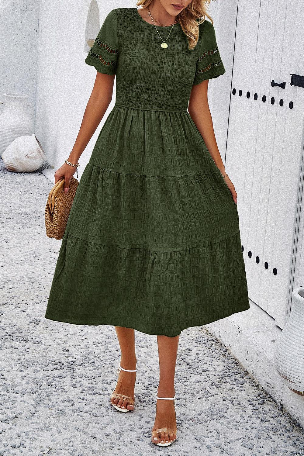 a woman in a green dress is standing outside