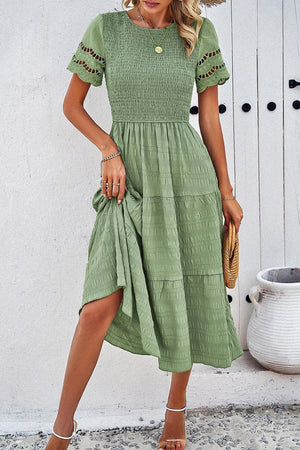 a woman wearing a green dress and straw hat
