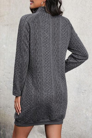 a woman wearing a gray cable knit sweater dress