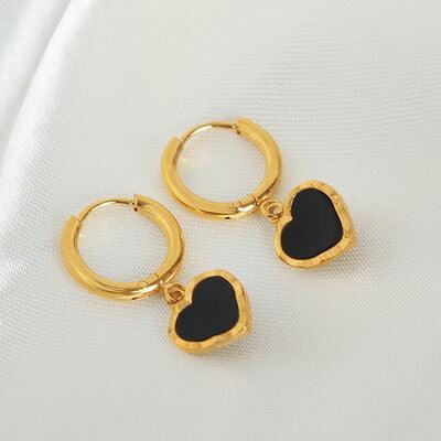 a pair of black heart shaped earrings sitting on top of a white cloth