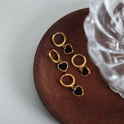 three pairs of gold earrings sitting on top of a wooden plate