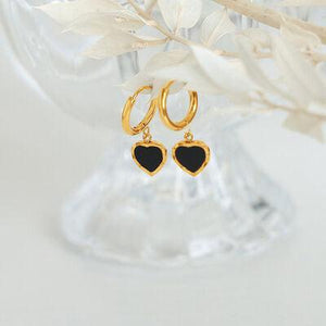 a pair of black and gold heart shaped earrings