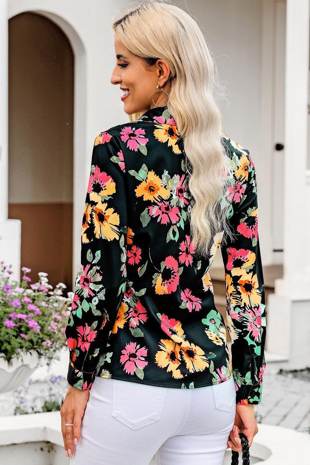 a woman wearing a black floral blouse and white pants